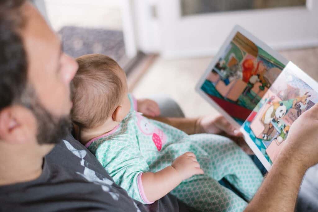 Photo of a father reading one of the best books for 1 year olds to his baby